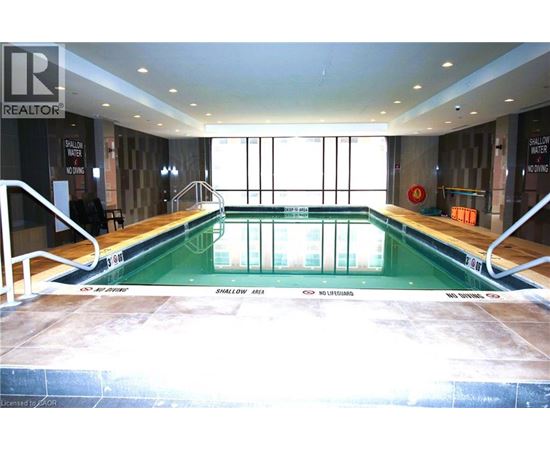 A large indoor swimming pool with a glass wall on one side.