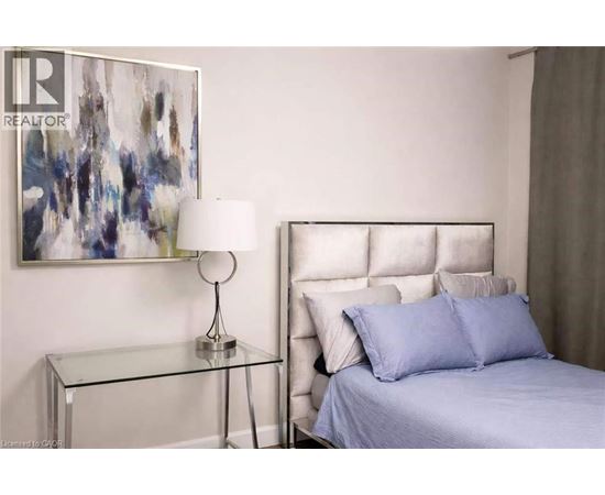 A bedroom with a bed, nightstand, and a painting on the wall.