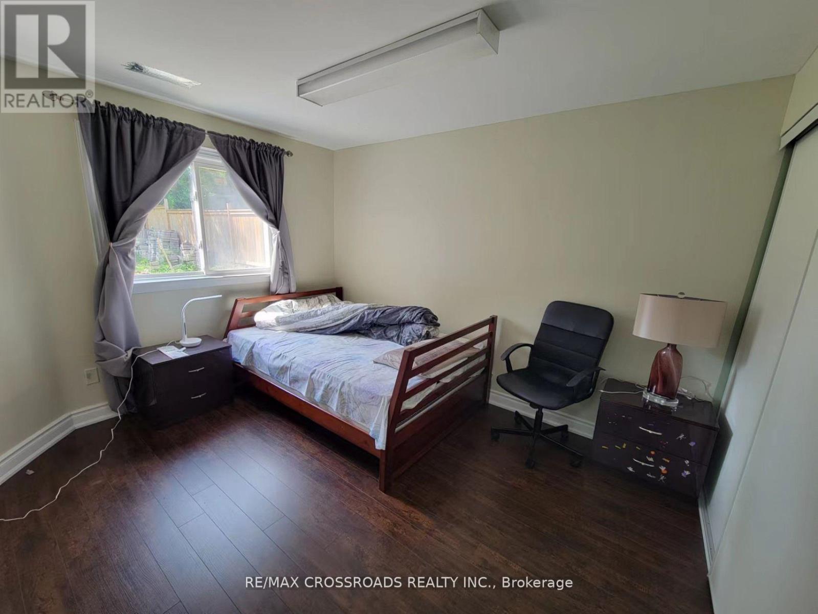 A bedroom with a bed, chair, and nightstand.