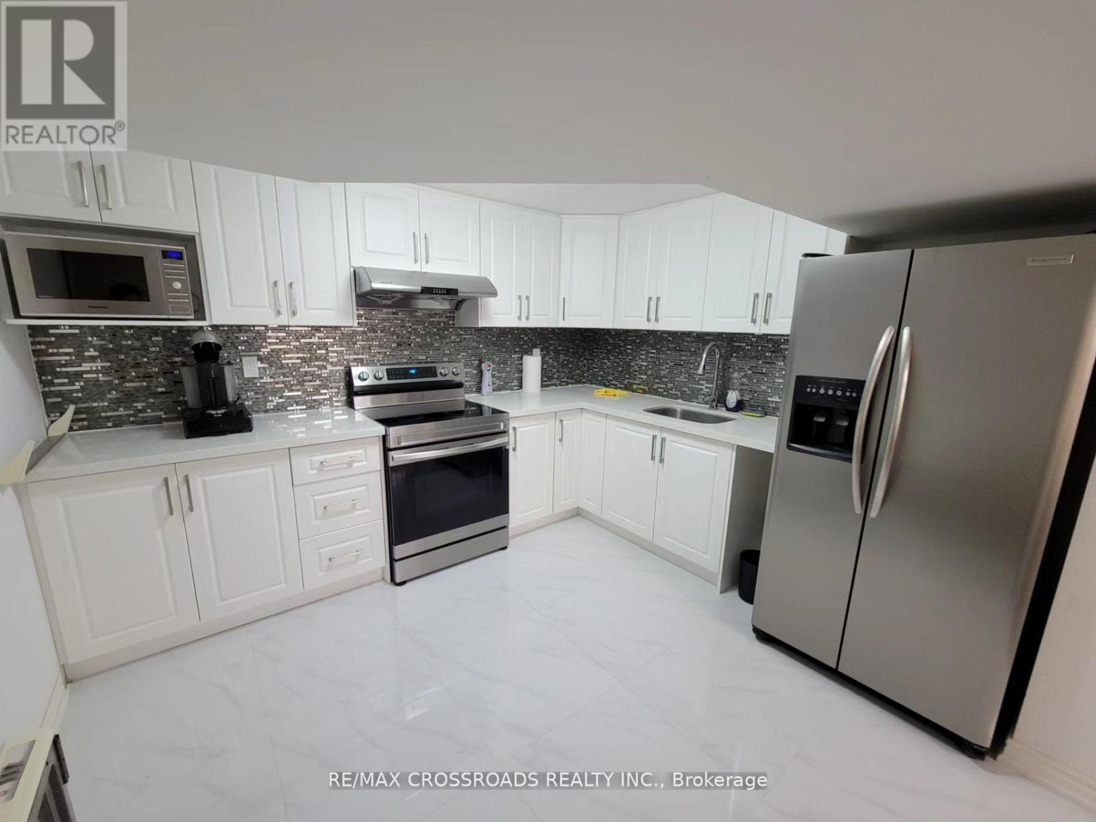 A kitchen with white cabinets and a black and white tiled backsplash.