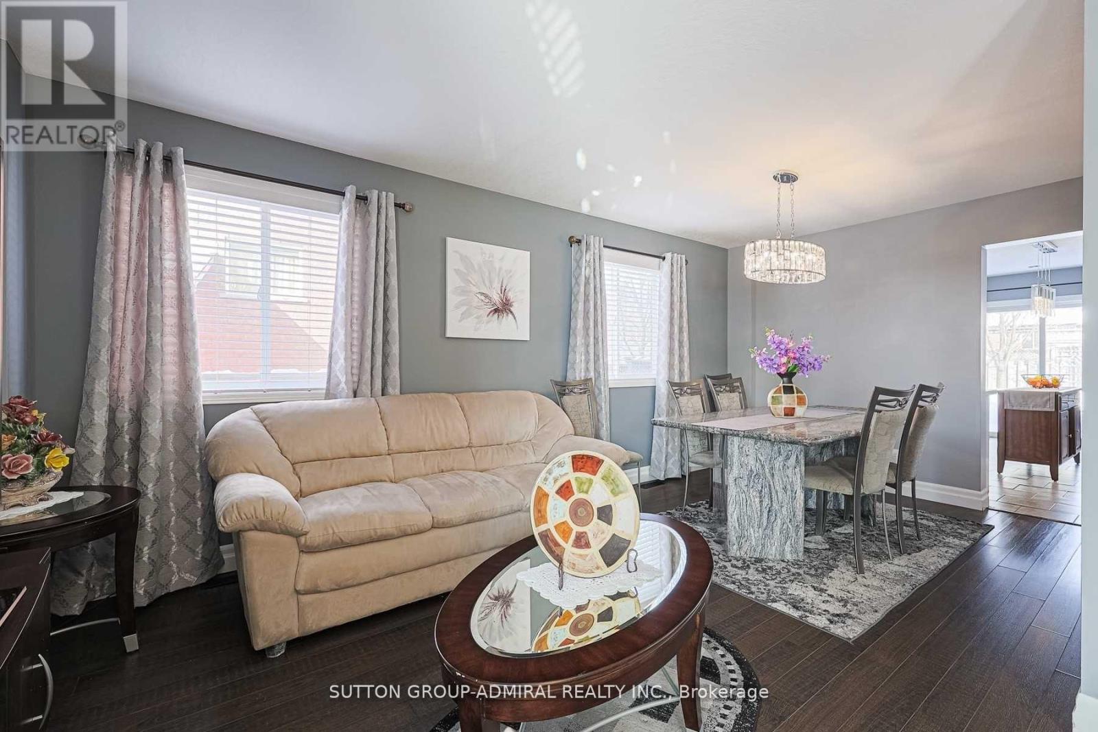 A living room with a beige sofa, a round coffee table with a decorative item on it, and a dining area with a table set for four.