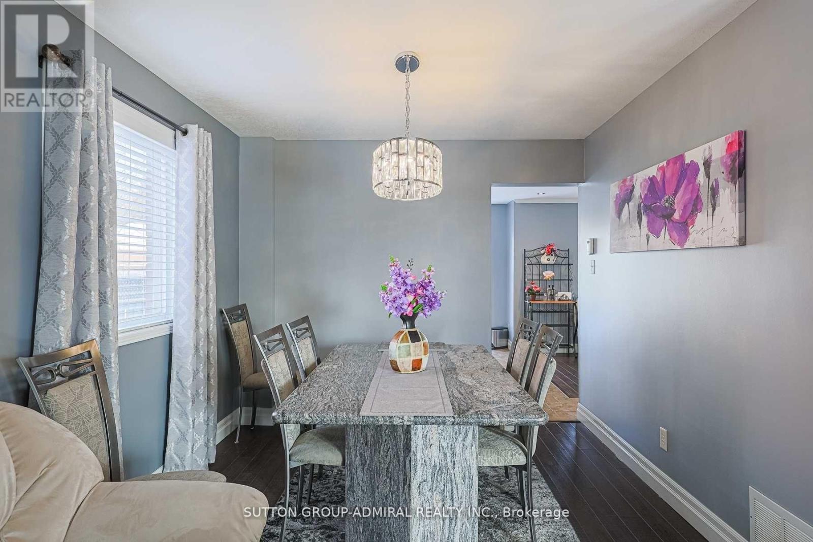 A dining room with a table set for six and a painting on the wall.