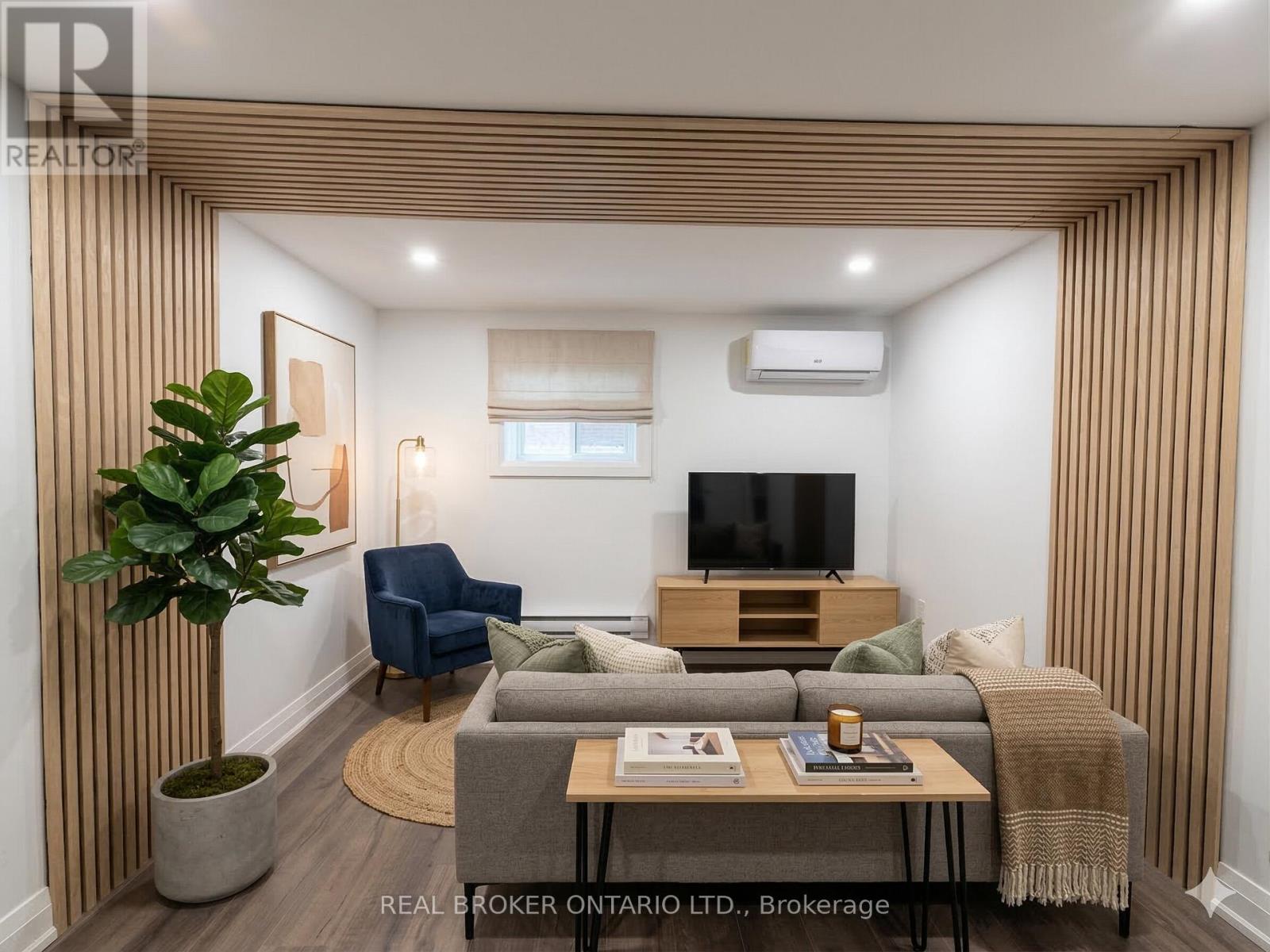 A living room with a grey couch, a blue chair, a wooden cabinet, and a television.