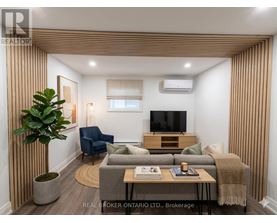 A living room with a grey couch, a blue chair, a wooden cabinet, and a television.