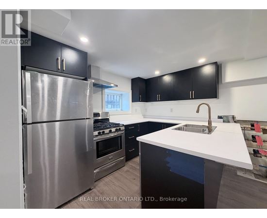 A modern kitchen with a stainless steel refrigerator and black cabinets.