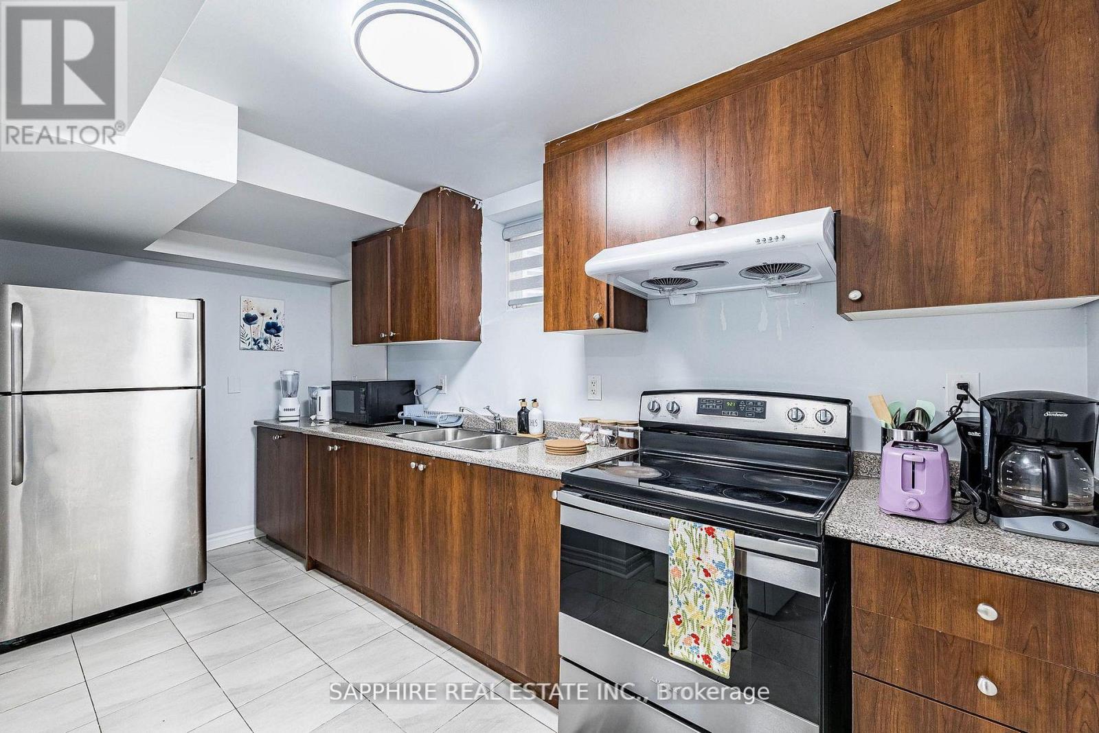 A kitchen with a refrigerator, oven, and sink.