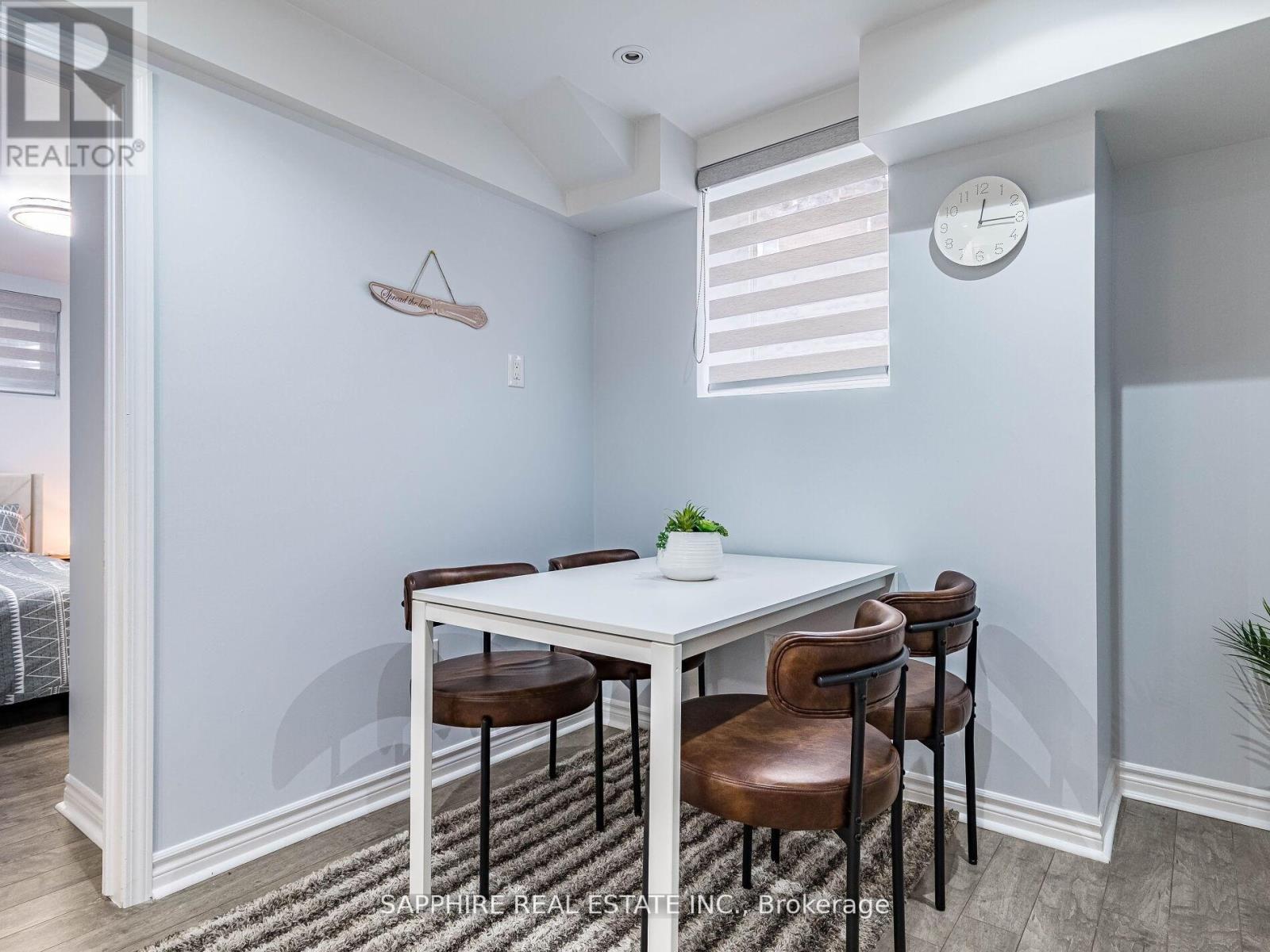 A dining room with a white table and brown chairs.