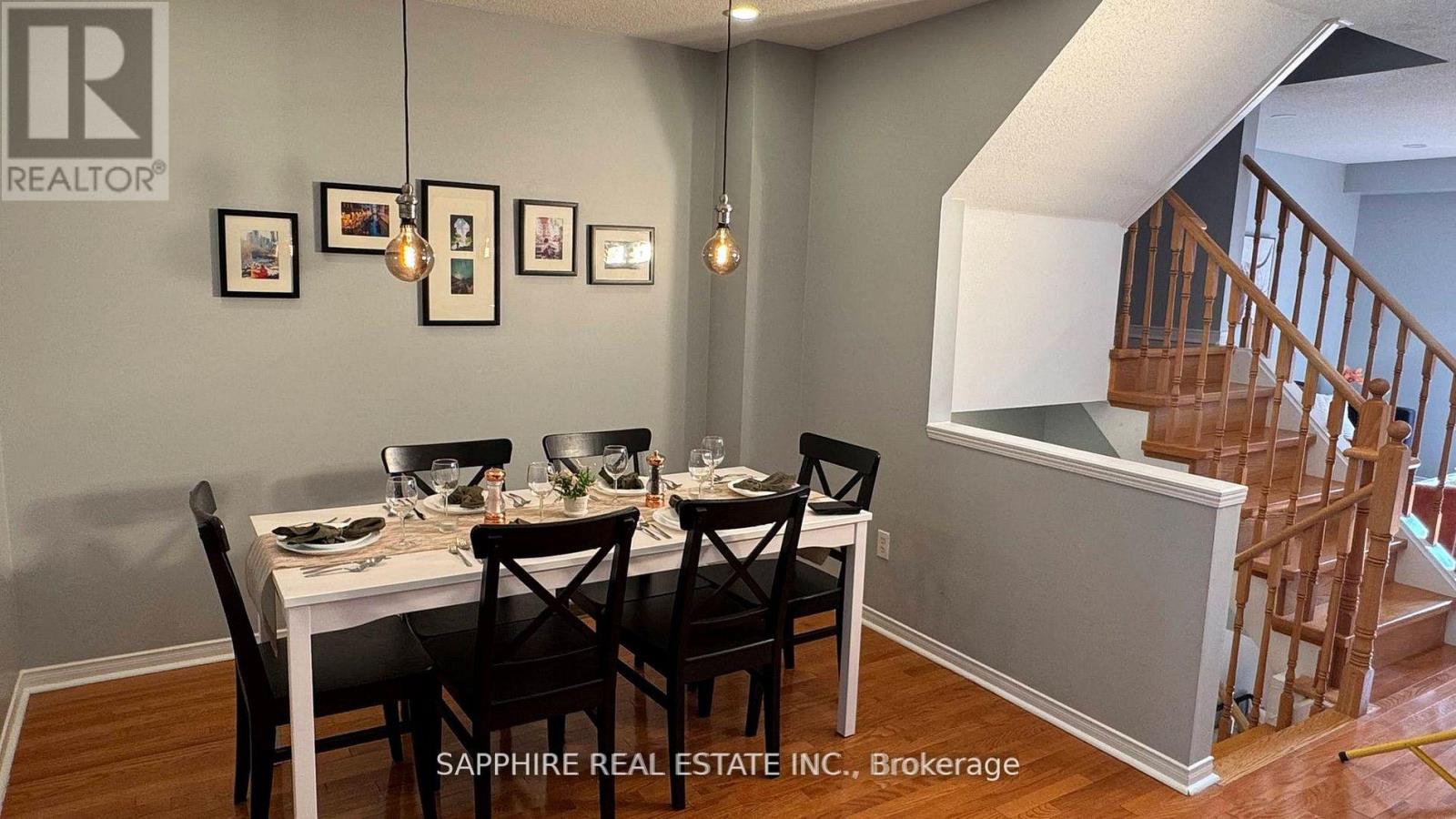 A dining room with a table set for four and a staircase in the background.