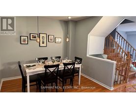 A dining room with a table set for four and a staircase in the background.