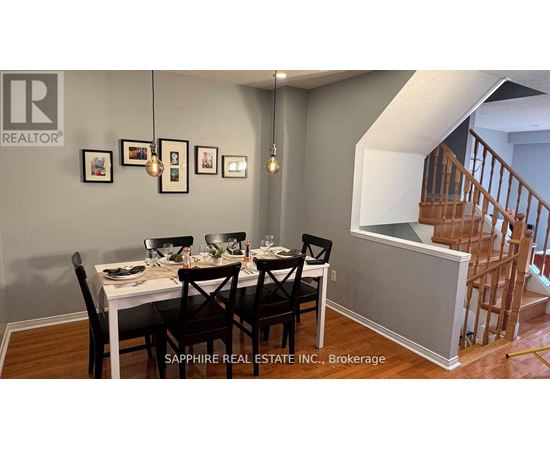 A dining room with a table set for four and a staircase in the background.