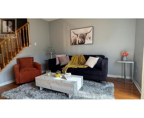 A living room with a black couch, a coffee table, and a painting of a cow on the wall.
