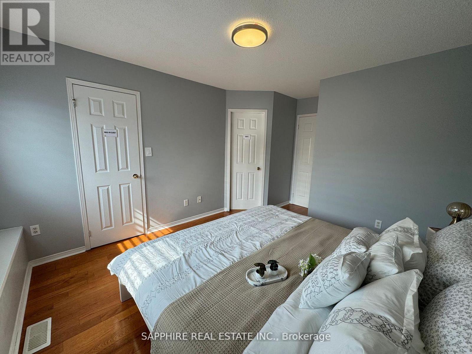 A bedroom with a bed in the middle and two doors on the wall.
