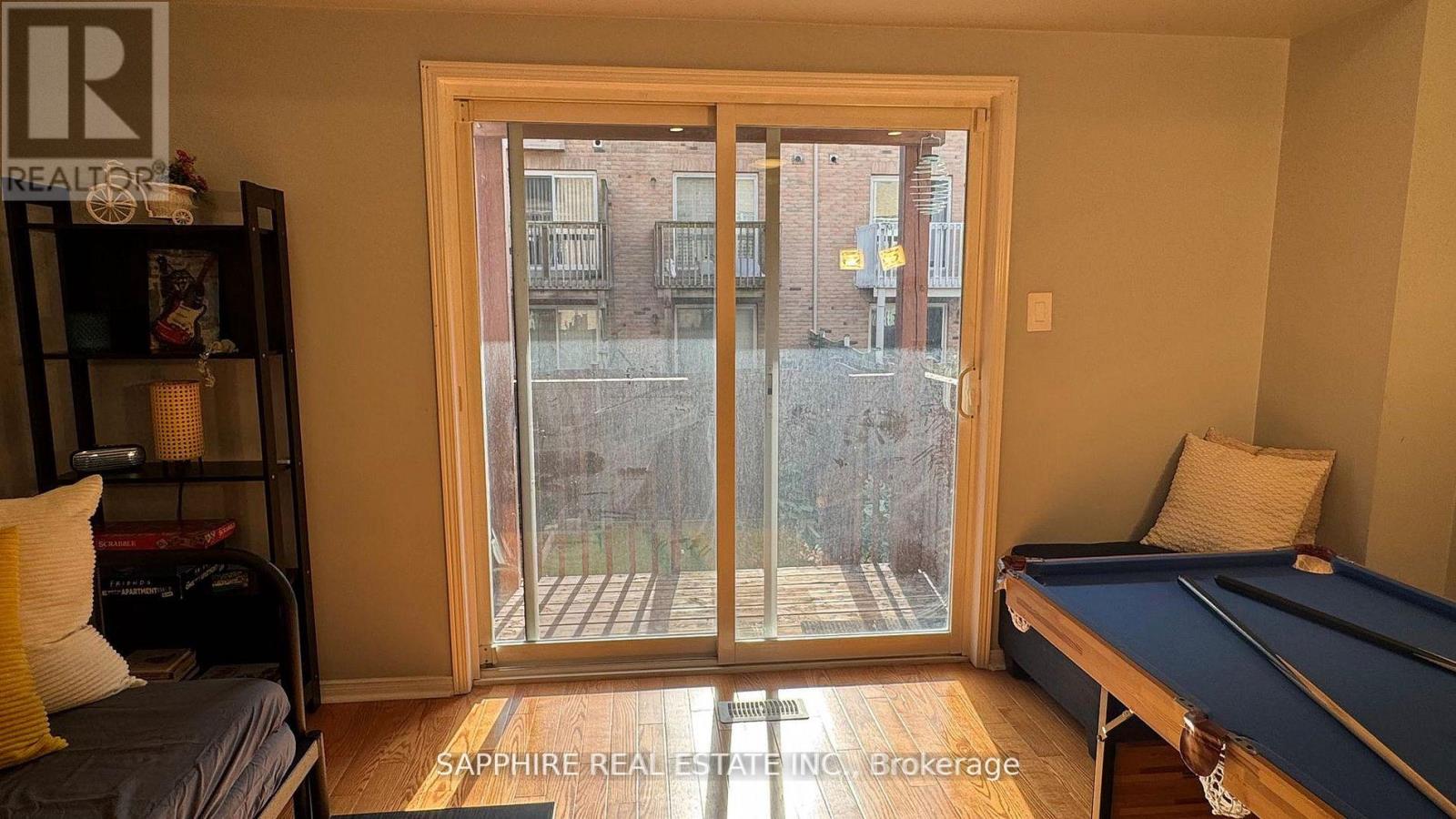 A room with a pool table and a view of a building outside through a glass door.