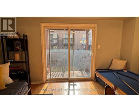 A room with a pool table and a view of a building outside through a glass door.