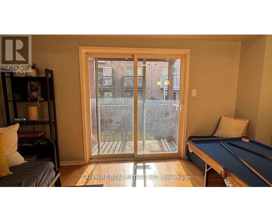 A room with a pool table and a view of a building outside through a glass door.