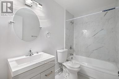 A white bathroom with a sink, toilet and bathtub.
