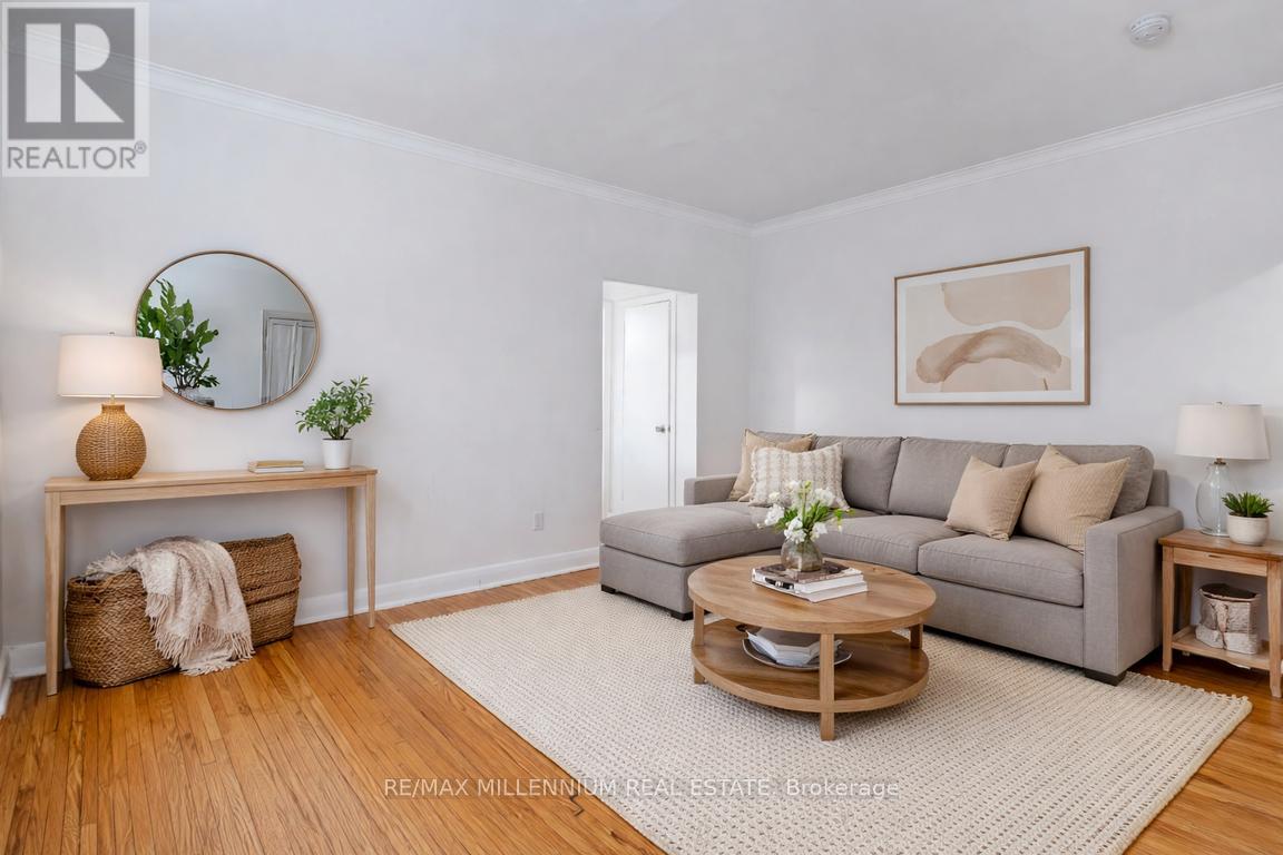A living room with a grey couch, a wooden coffee table, and a round mirror on the wall.