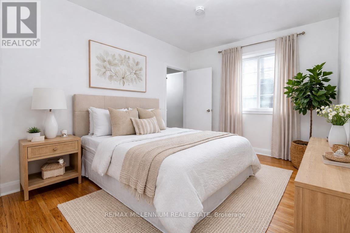 A bedroom with a large bed, a nightstand, and a plant.