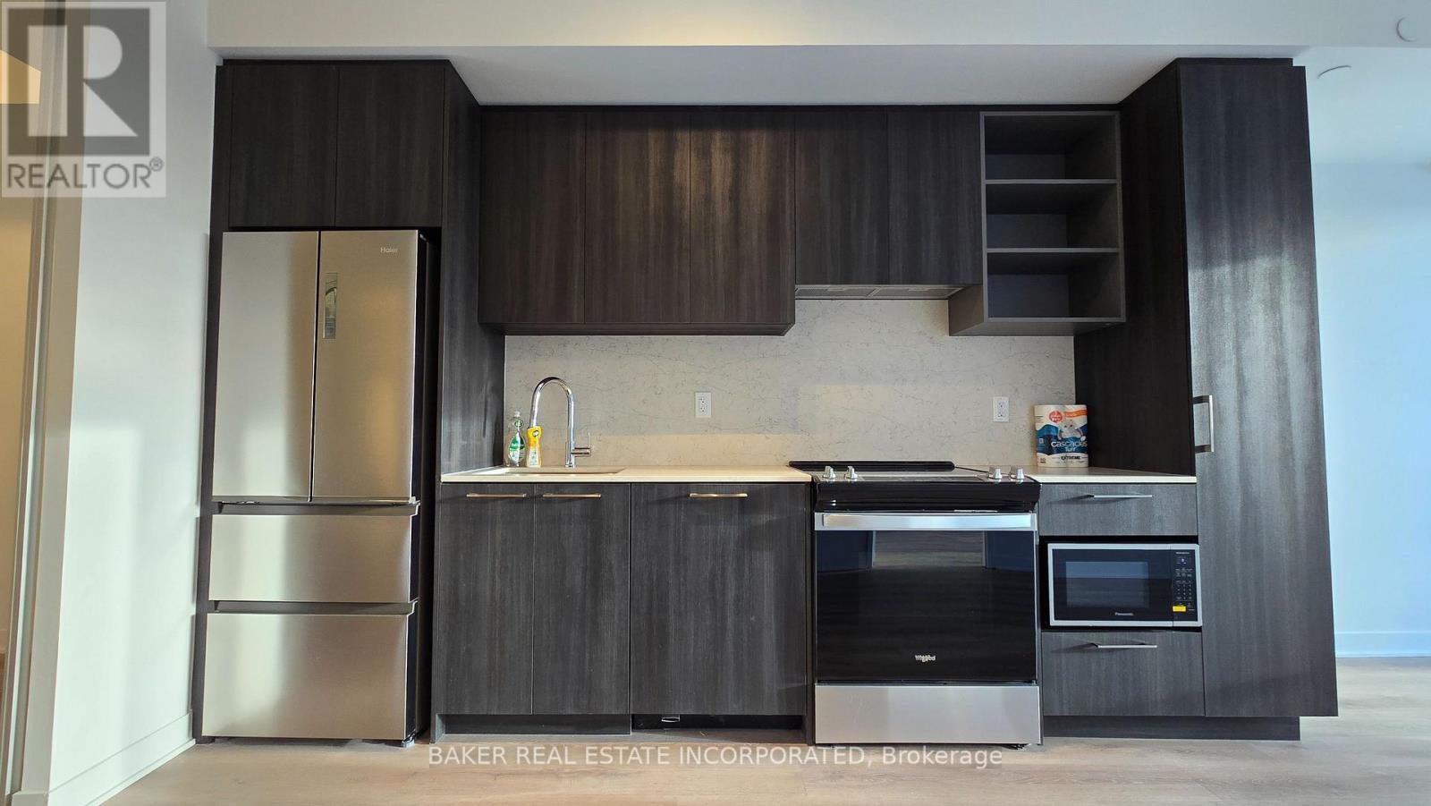 A modern kitchen with dark wood cabinets and stainless steel appliances.