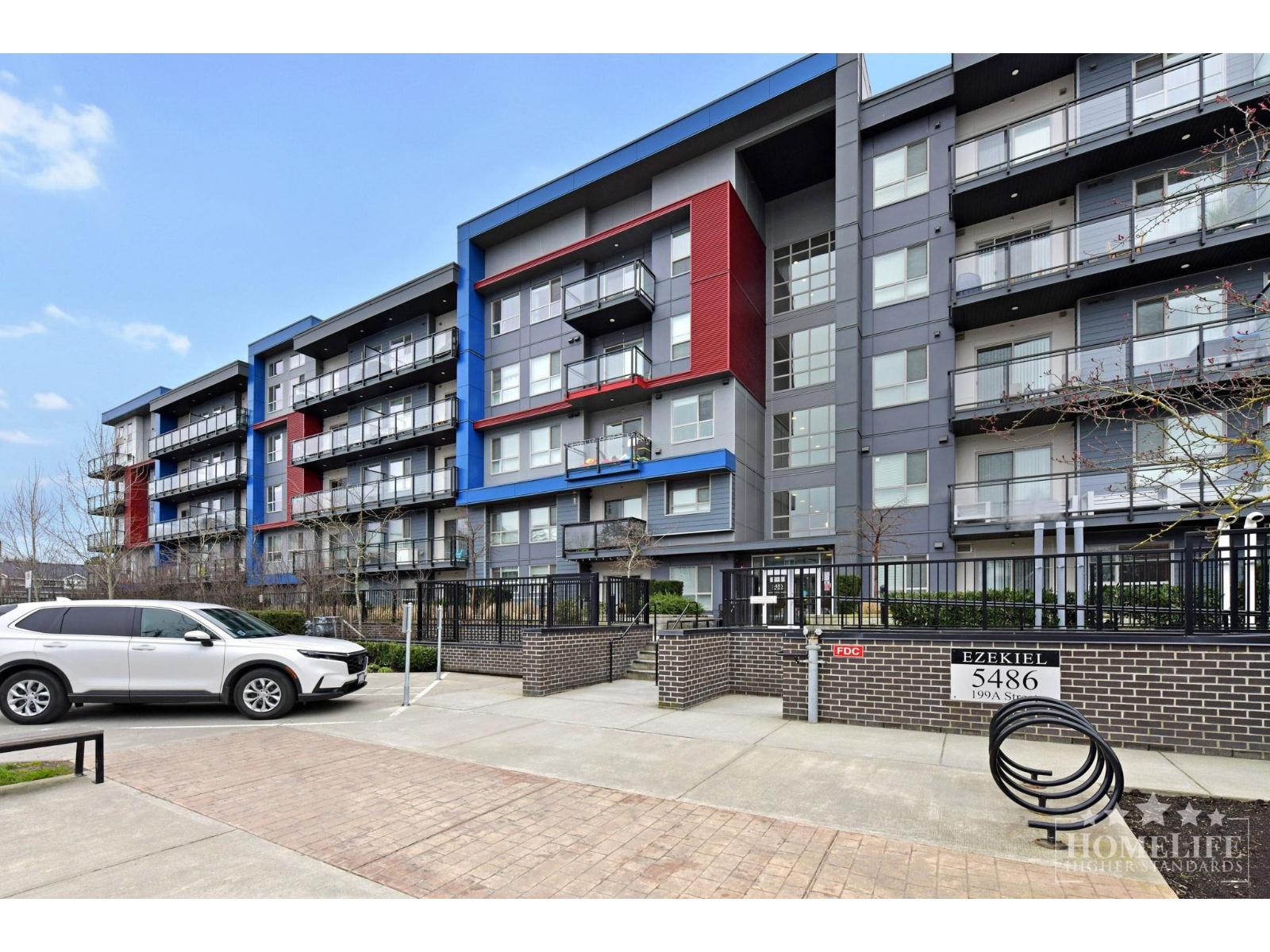 A modern apartment building with a white car parked in front.
