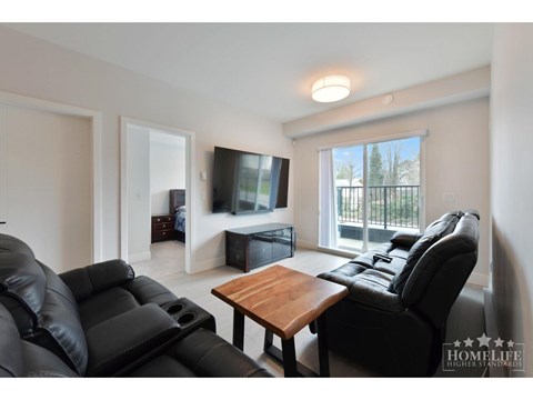 A black leather couch sits in a living room with a wooden table and a television.