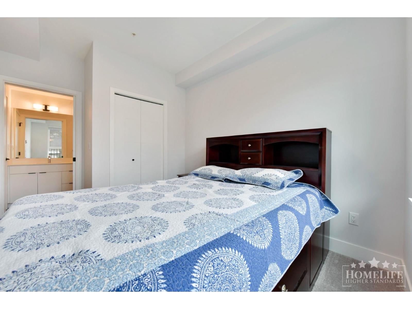 A bedroom with a bed covered in a blue and white patterned comforter.