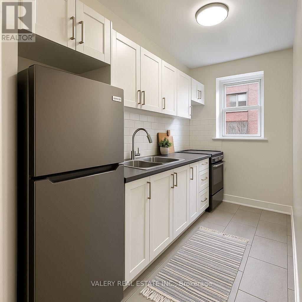 A kitchen with white cabinets and a black refrigerator.