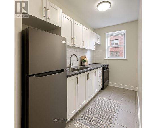 A kitchen with white cabinets and a black refrigerator.