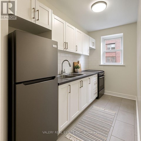 A kitchen with white cabinets and a black refrigerator.