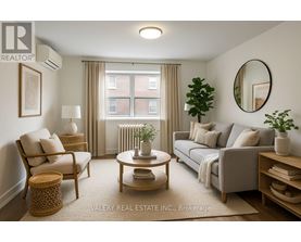 A living room with a grey couch, a wooden coffee table, a chair, a potted plant, and a round mirror on the wall.
