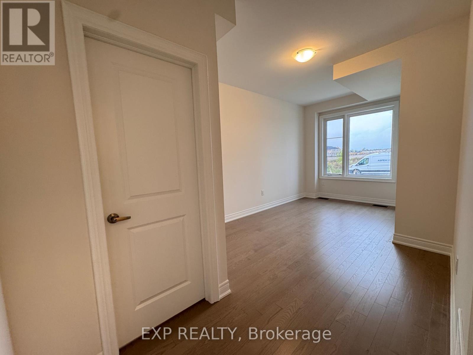 A room with a door and a window overlooking a parking lot.