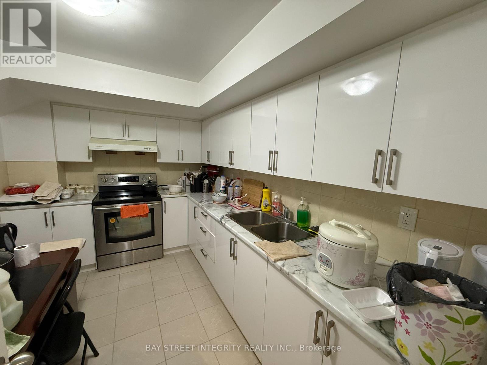 A kitchen with white cabinets and a variety of appliances and items on the counter.