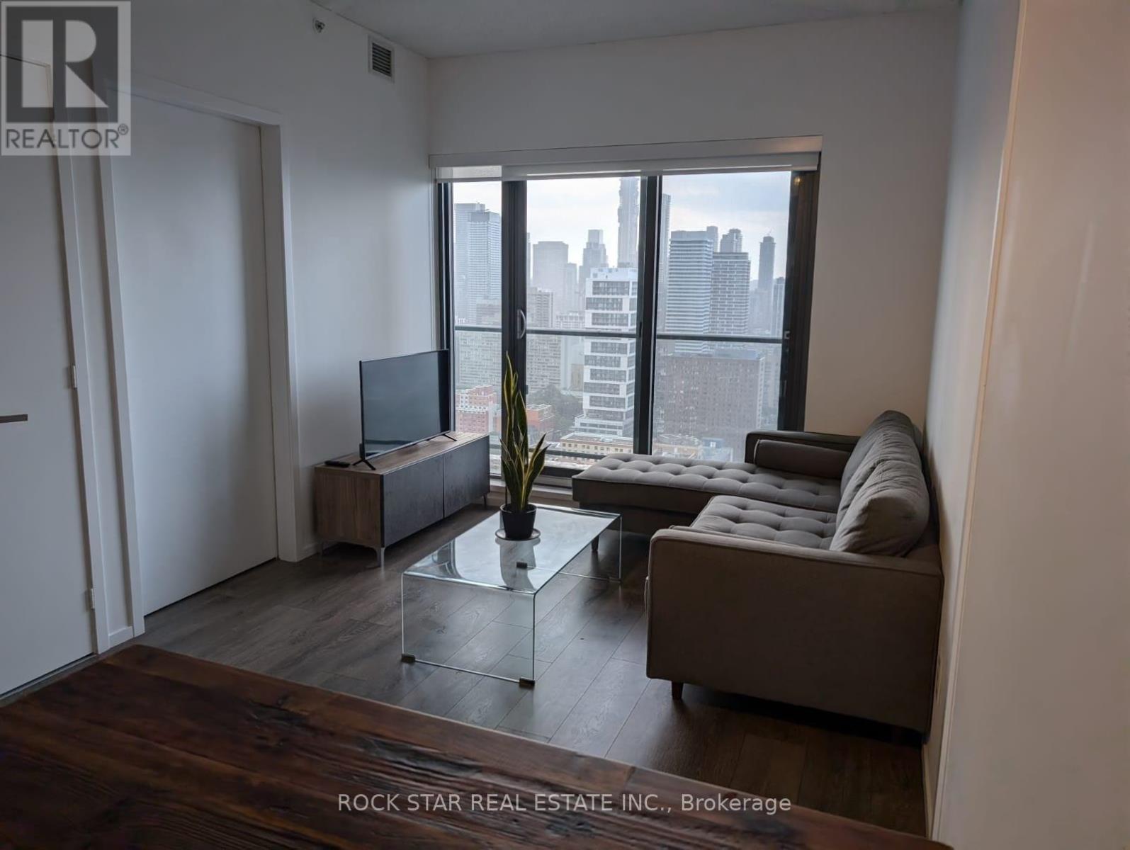 A living room with a couch, a glass table, and a television.