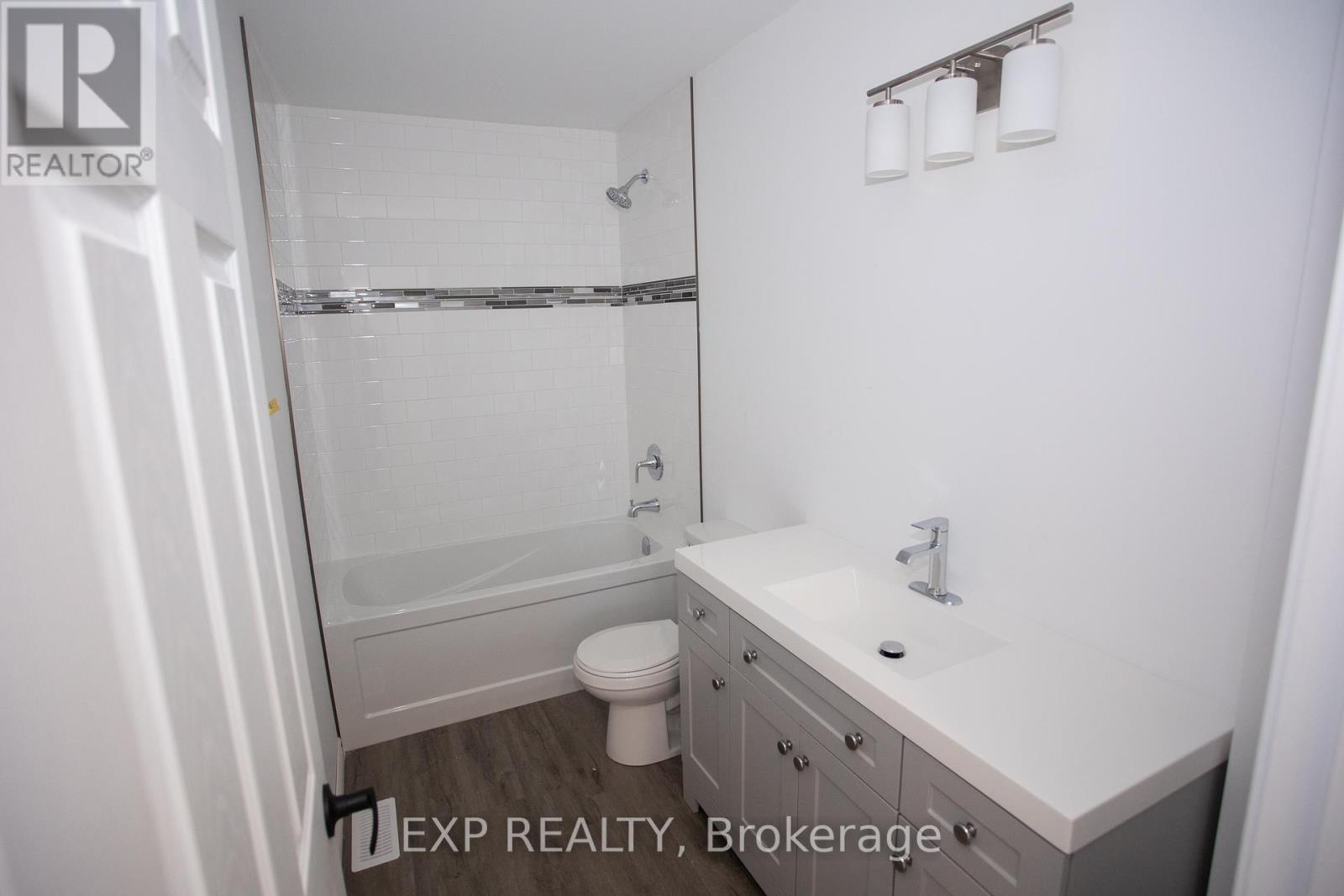 A white bathroom with a toilet, sink, and shower.