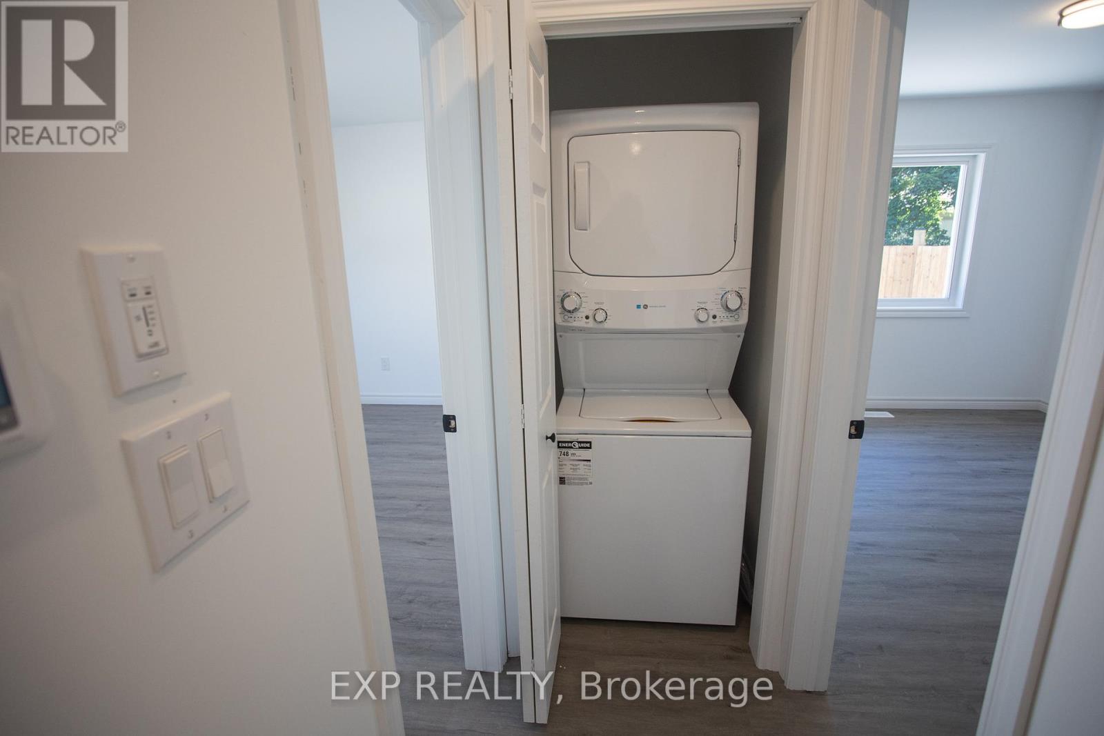 A white toilet is in a small room with EXP Realty Brokerage written on the bottom.