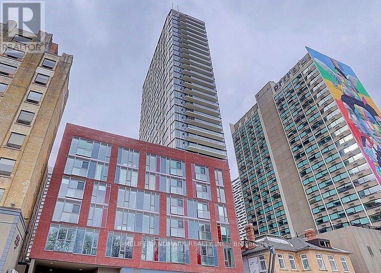 A tall building with a glass facade stands in front of a red brick building.