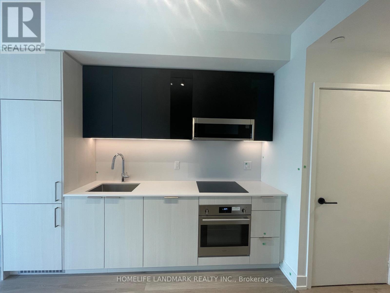 A modern kitchen with white cabinets and black countertops.
