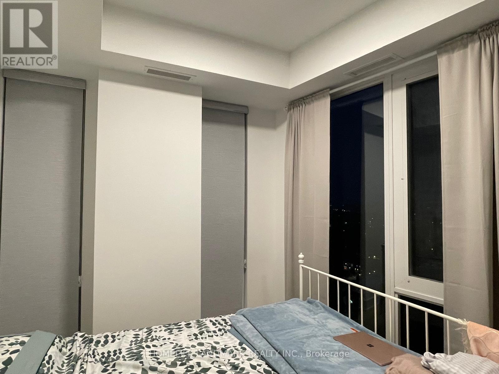 A bedroom with a bed, a window with curtains, and a sliding door.