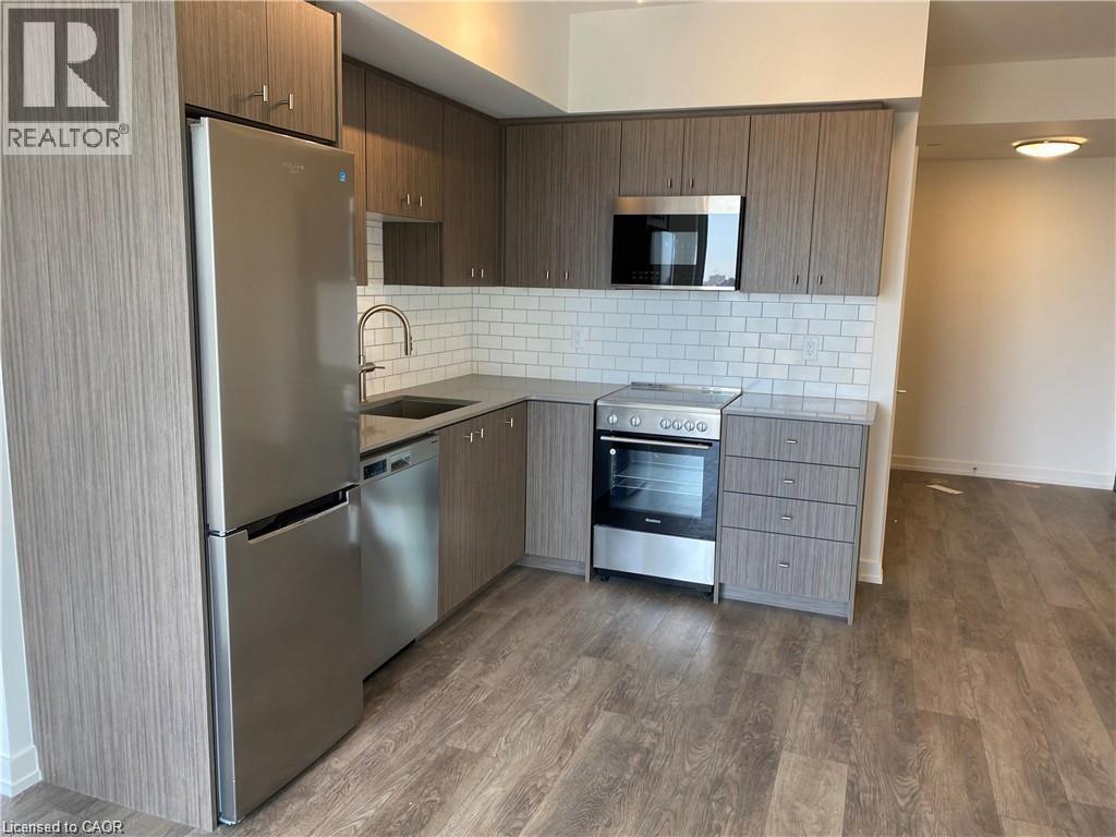 A kitchen with a refrigerator, oven, and microwave.