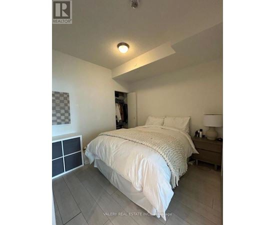 A bedroom with a bed, nightstand, and lamp.