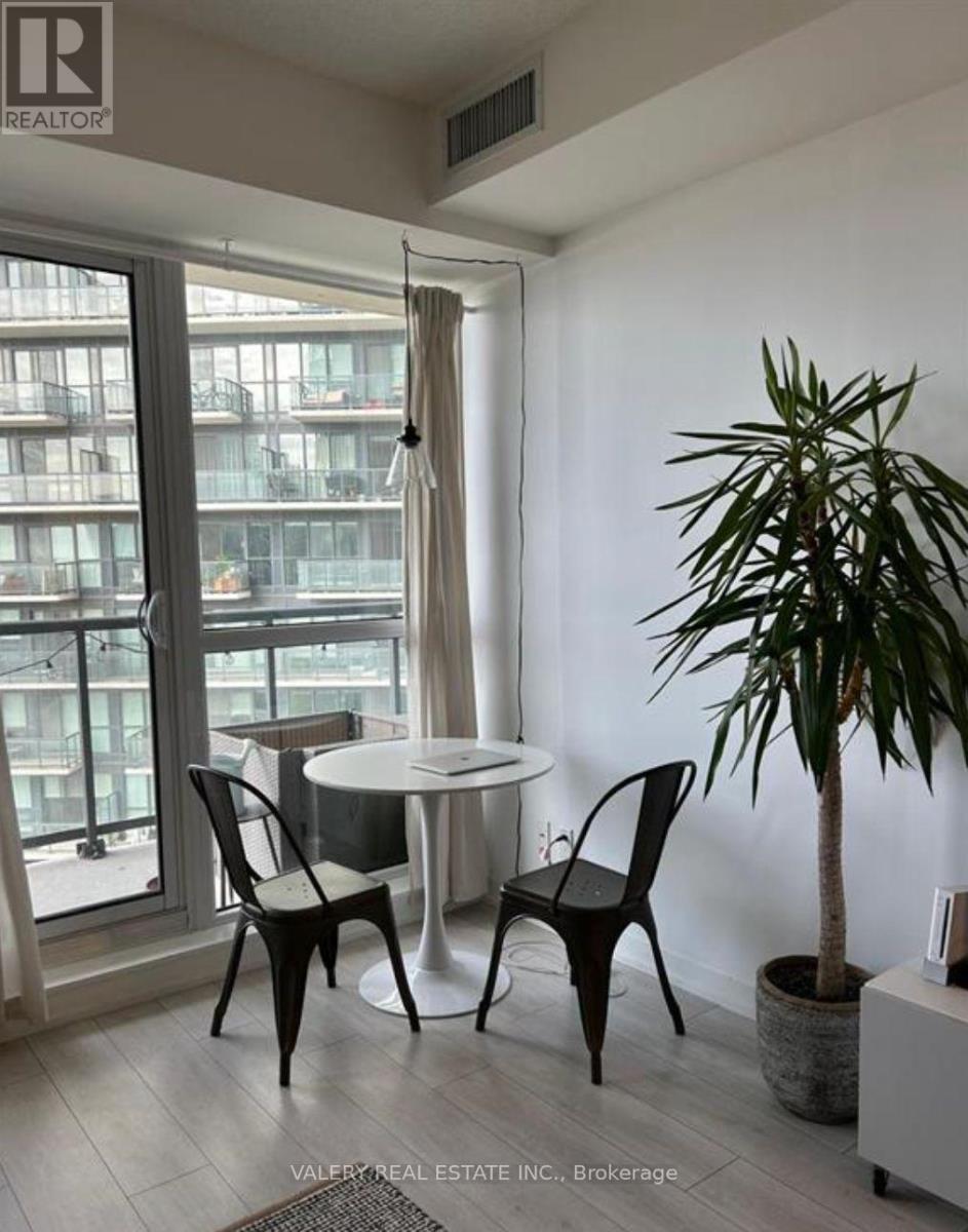 A living room with a table and chairs and a plant.