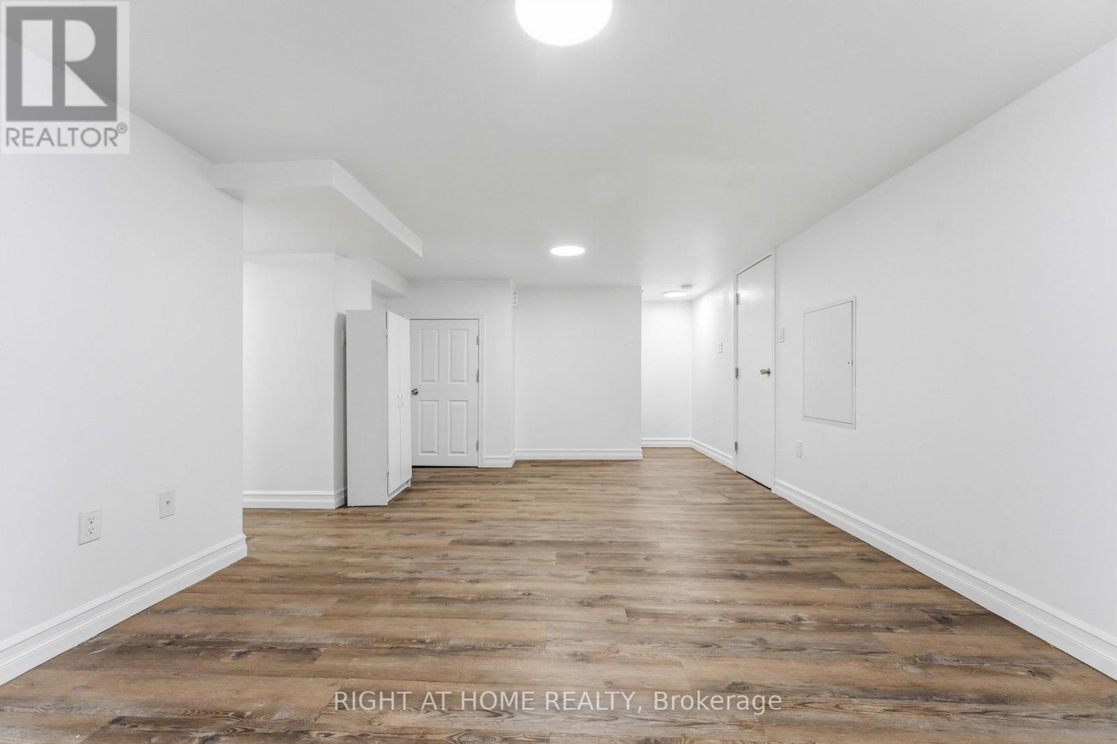 A spacious room with wooden flooring and white walls.