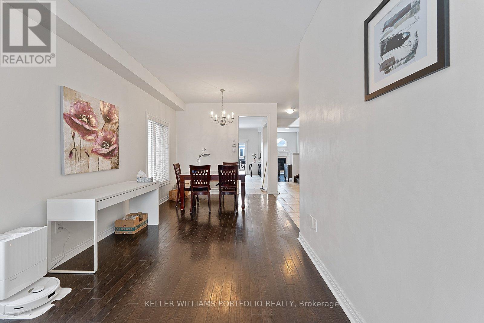 A spacious room with a long wooden floor and a white wall with a framed picture hanging on it.
