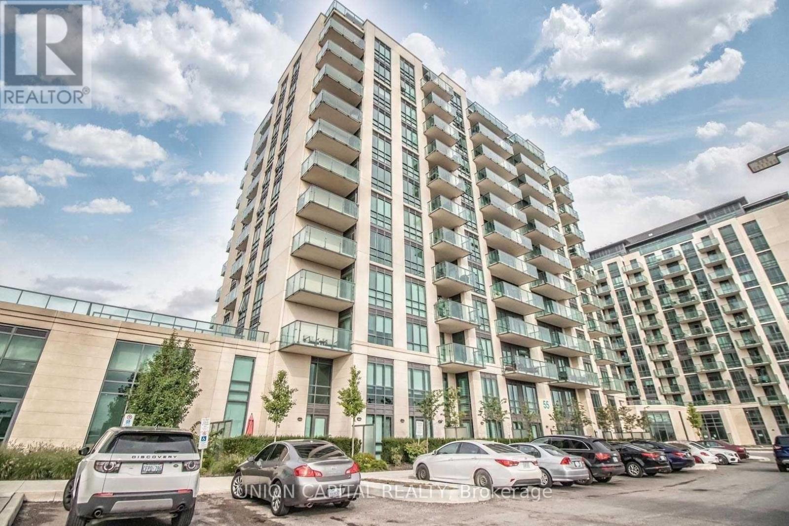 A tall residential building with a parking lot in front.