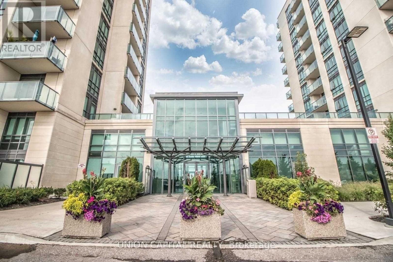 The front of a building with a glass entrance and a balcony on the left side.