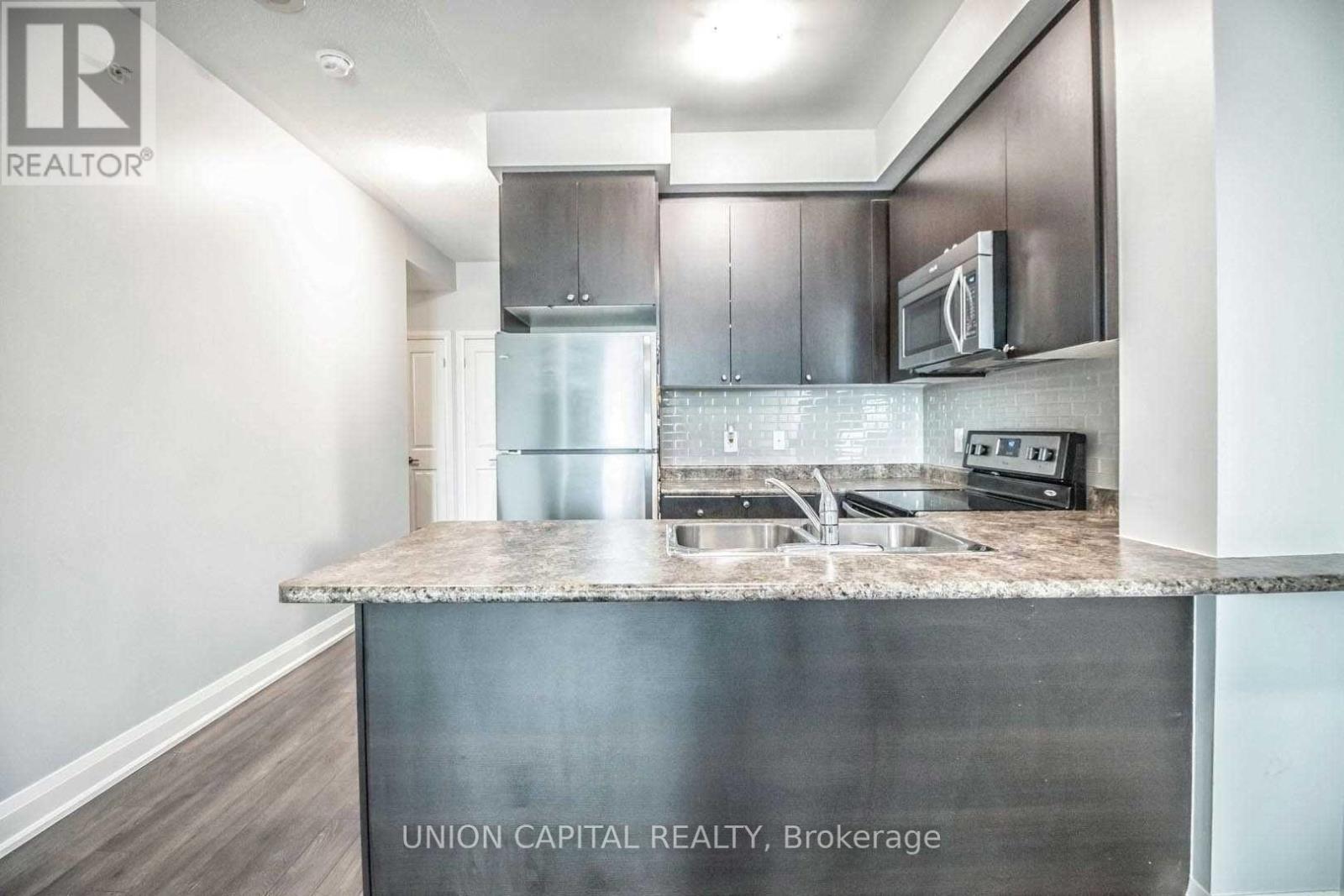 A kitchen with a stainless steel island and a refrigerator.