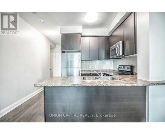 A kitchen with a stainless steel island and a refrigerator.