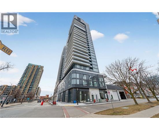 A tall building with a glass facade stands in front of a smaller building with a white facade.