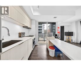 A modern kitchen with white cabinets and a wooden floor.