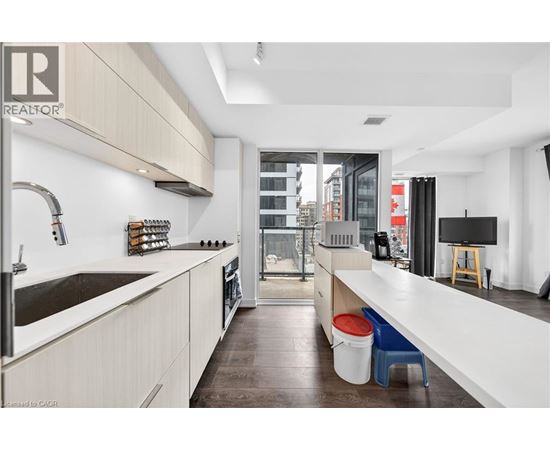 A modern kitchen with white cabinets and a wooden floor.